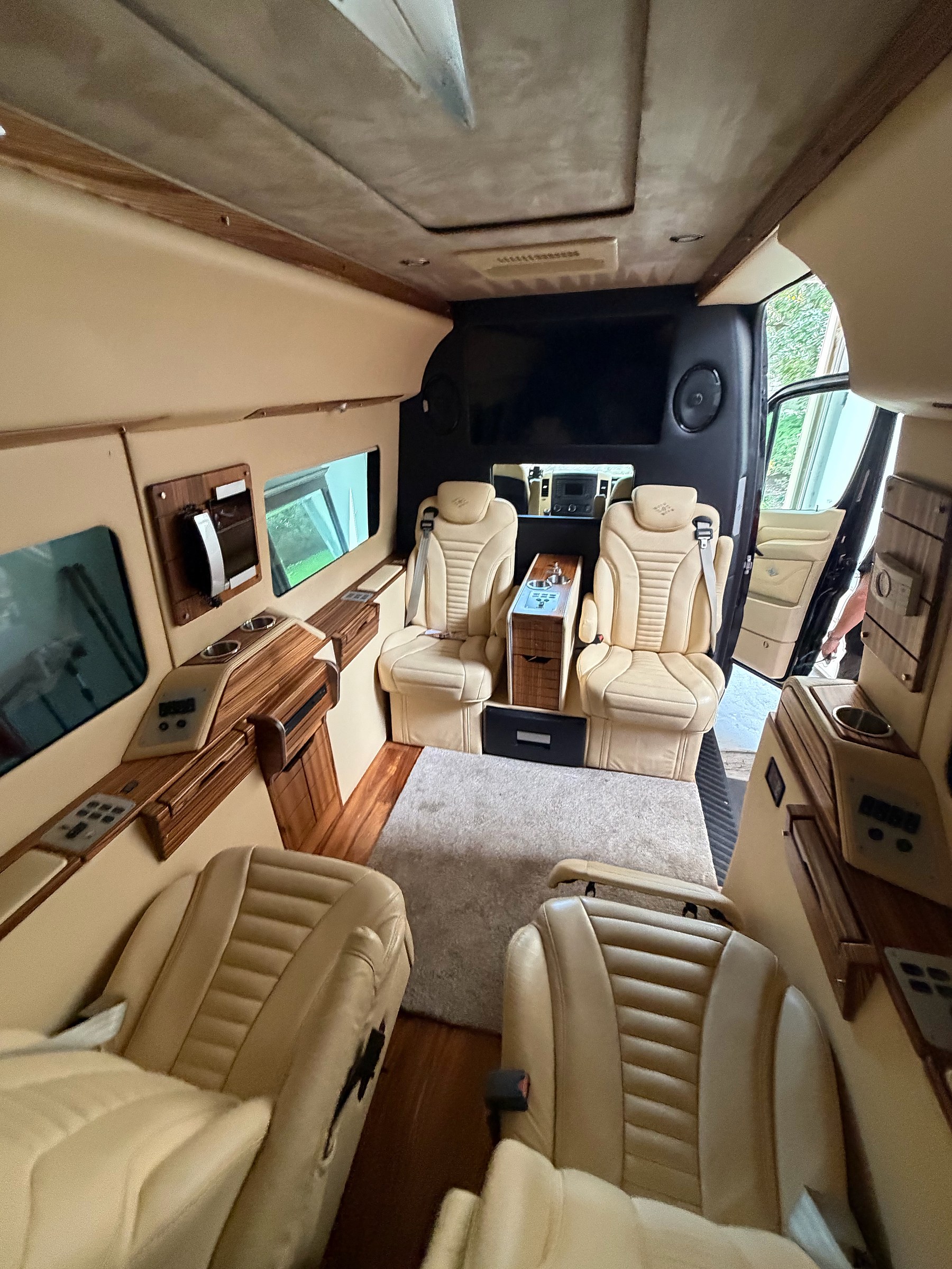 Cream leather captain chairs and wood-grain consoles inside the Sprinter